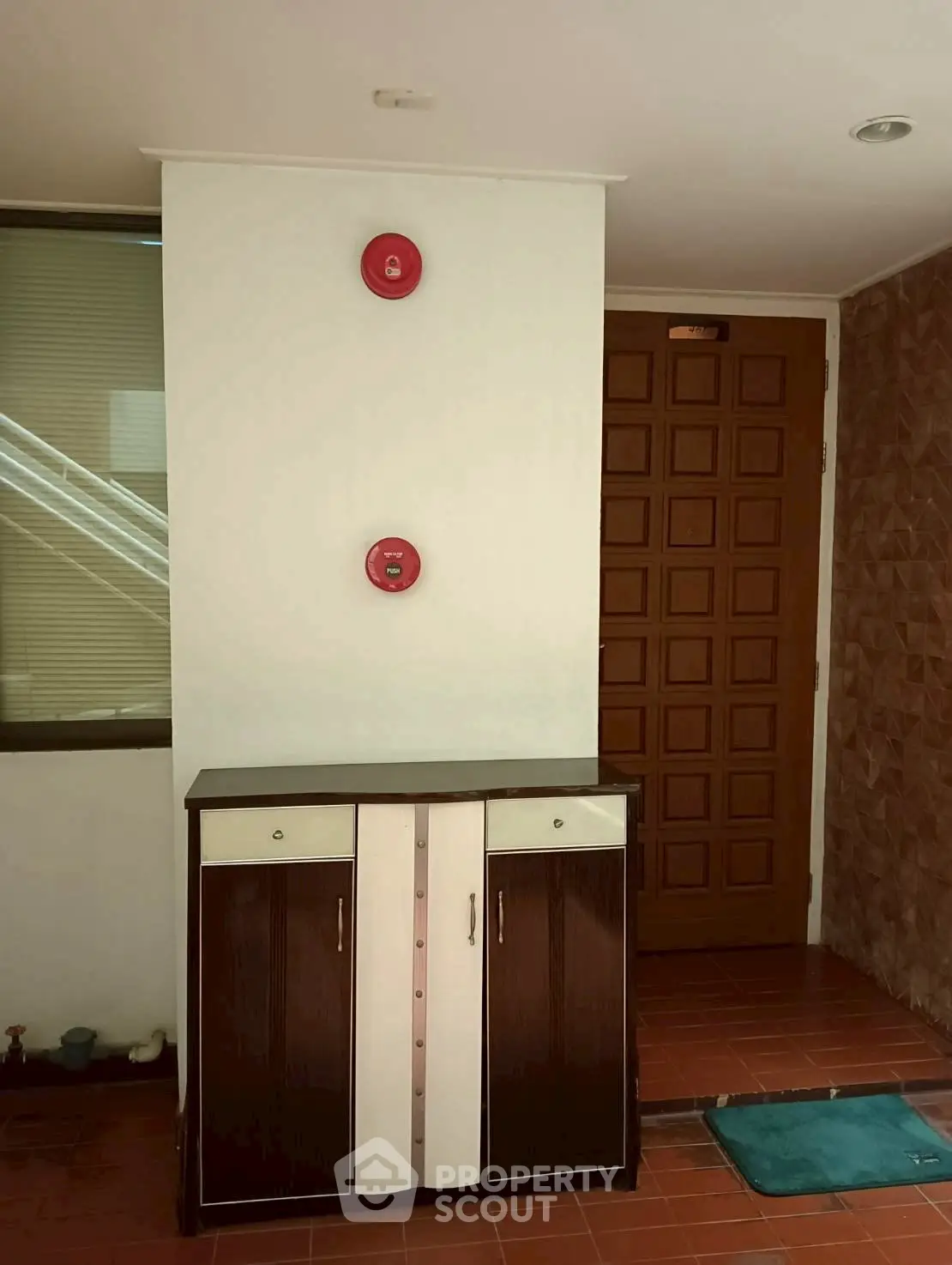 Stylish entrance with modern wooden door and sleek cabinet in a well-lit hallway.