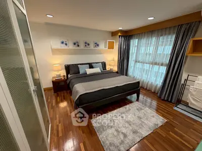 Elegant bedroom with wooden flooring and large windows for natural light