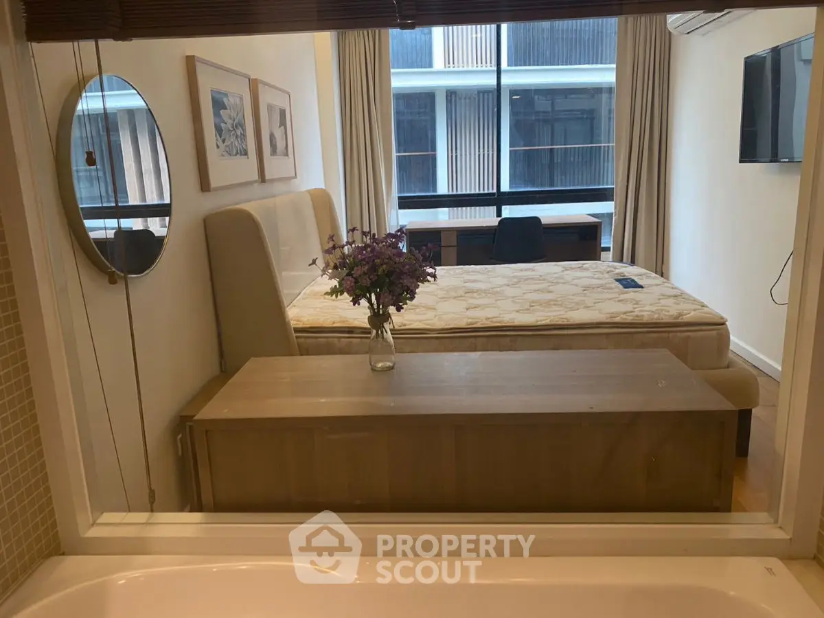 Modern bedroom with large window and stylish decor, featuring a comfortable bed and elegant furnishings.