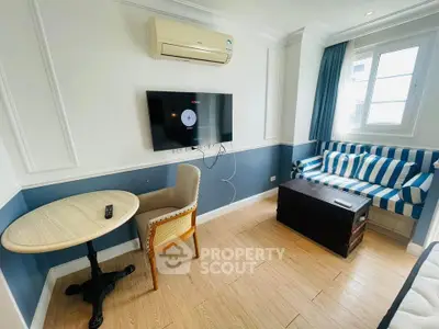 Charming living room with stylish decor, featuring a cozy sofa, wall-mounted TV, and elegant round table.