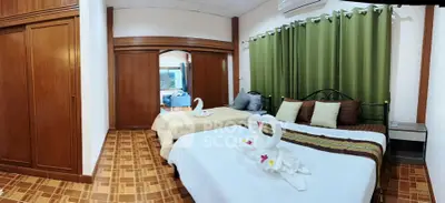 Spacious bedroom with elegant decor and twin beds, featuring wooden flooring and green curtains.