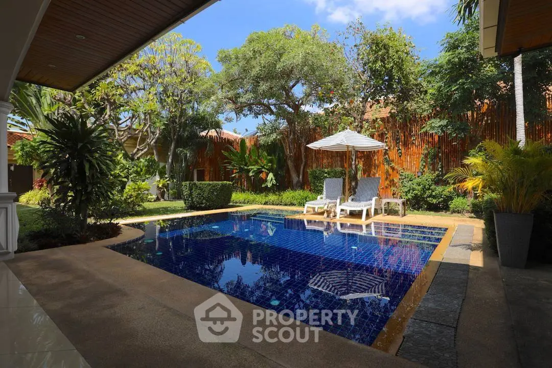 Luxurious private pool area with lush greenery and sun loungers, perfect for relaxation and leisure.