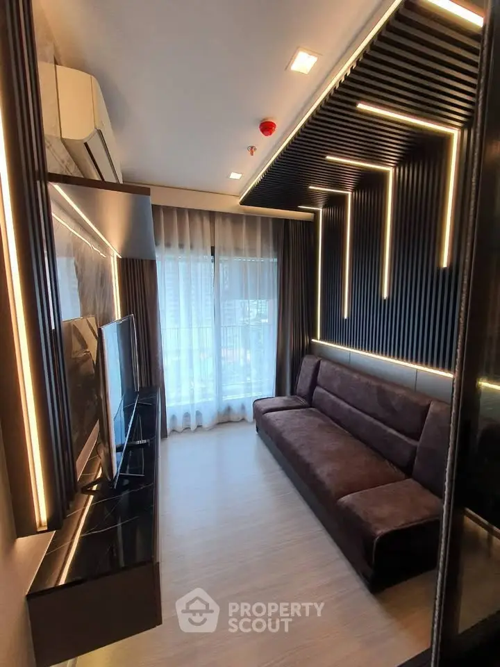 Modern living room with sleek lighting and contemporary design, featuring a comfortable sofa and large TV.