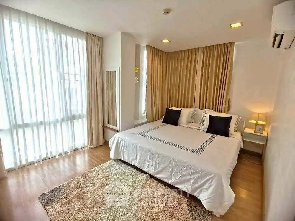 Spacious bedroom with elegant decor and large windows for natural light.