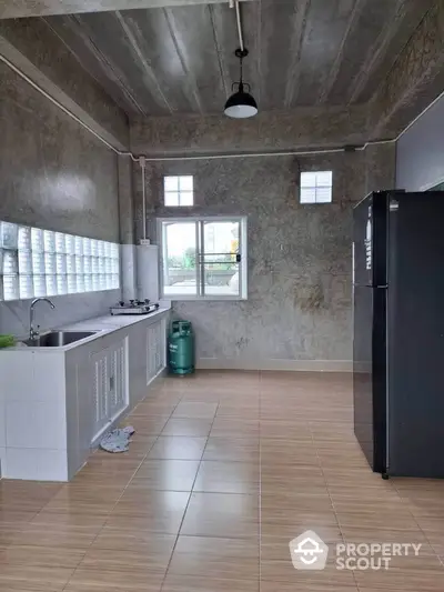 Spacious industrial-style kitchen with gas stove and large refrigerator