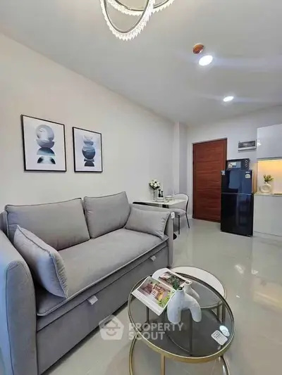 Modern living room with sleek gray sofa, stylish decor, and compact kitchen area.