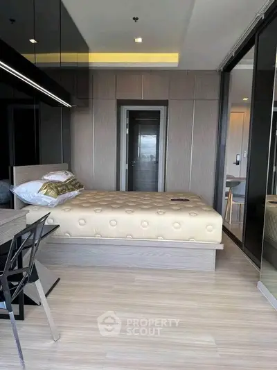 Modern bedroom with sleek design and mirrored wardrobe in a stylish apartment.