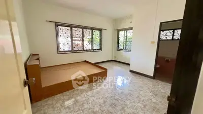Spacious bedroom with large windows and tiled flooring in a serene setting.