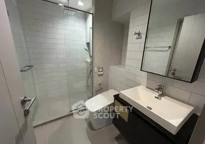 Modern bathroom with sleek design, featuring a glass shower and contemporary fixtures.