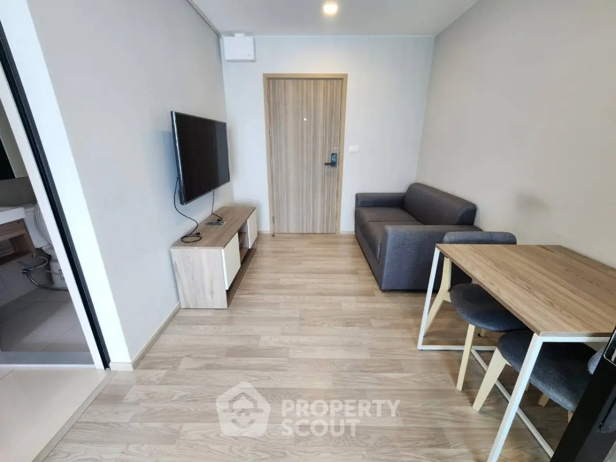 Modern living room with wooden flooring, cozy sofa, and wall-mounted TV