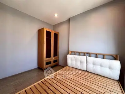 Minimalist bedroom with wooden bed frame and wardrobe, perfect for cozy living.