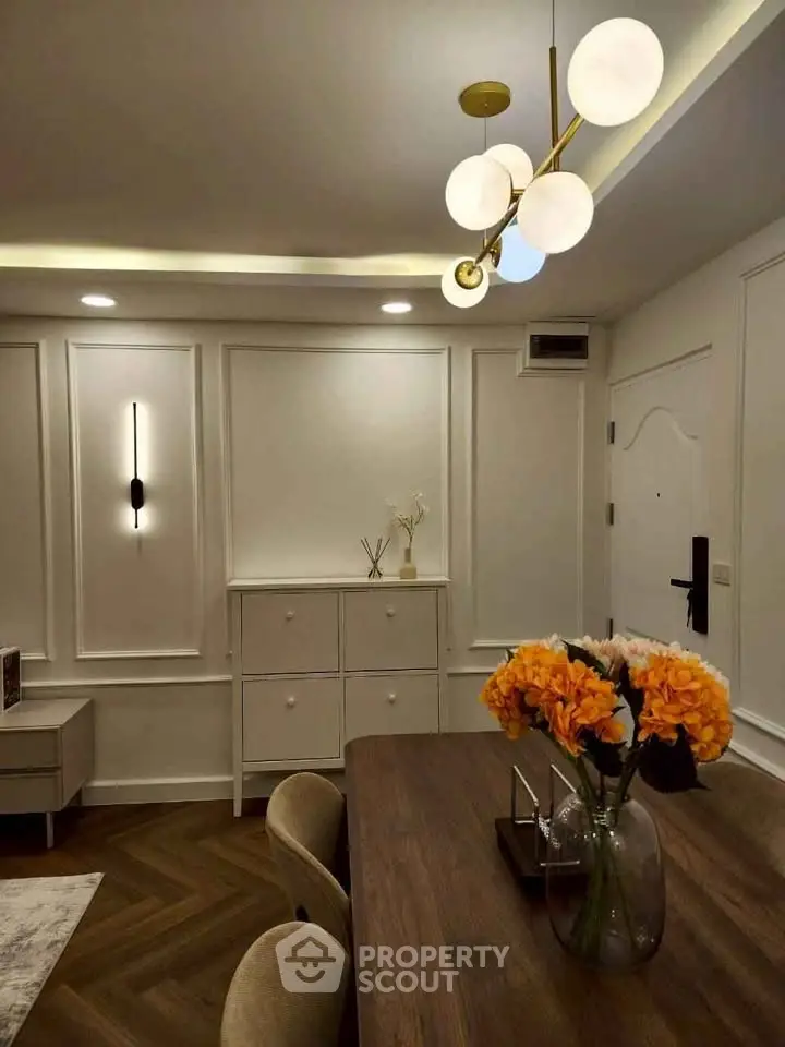 Elegant dining area with modern lighting and floral centerpiece in a stylish apartment.