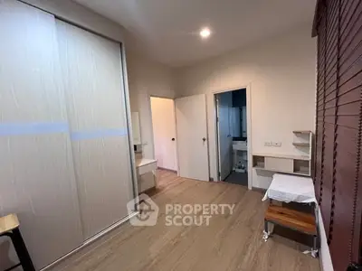 Spacious bedroom with wooden flooring and built-in wardrobe in modern apartment.