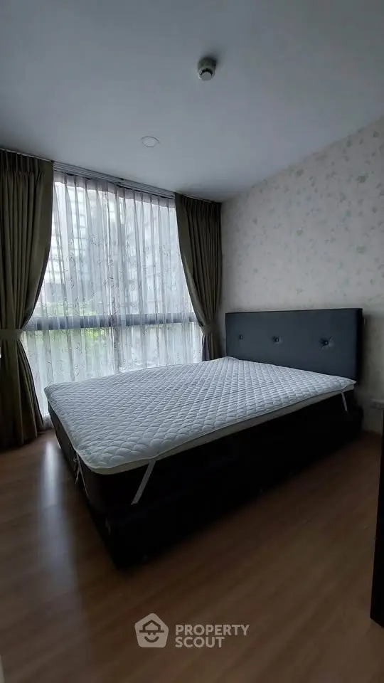 Cozy bedroom with large window and elegant curtains, featuring a comfortable bed and stylish decor.