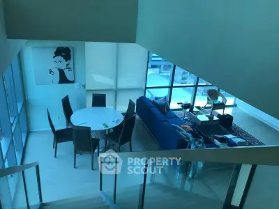 Modern living room with stylish decor and large windows offering natural light and city views.