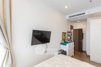 Modern bedroom with wall-mounted TV and stylish decor in a cozy apartment.
