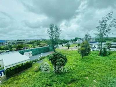 Expansive view of lush green landscape with modern buildings under cloudy sky.