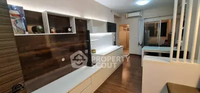 Modern living room with sleek wooden flooring and stylish built-in storage units.