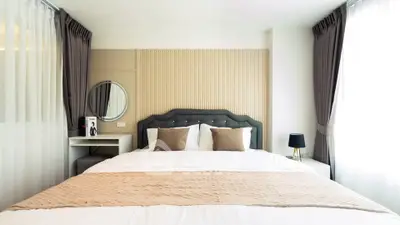 Elegant bedroom with modern decor, featuring a plush bed, stylish headboard, and natural light from large windows.