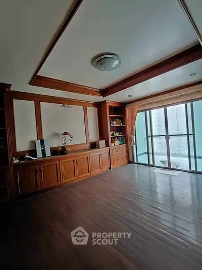 Spacious living room with wooden flooring and large windows offering city views.
