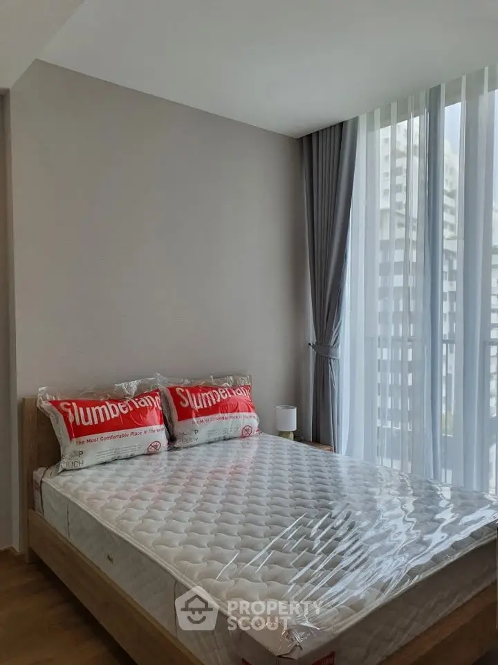 Modern bedroom with large windows and natural light in a high-rise apartment.