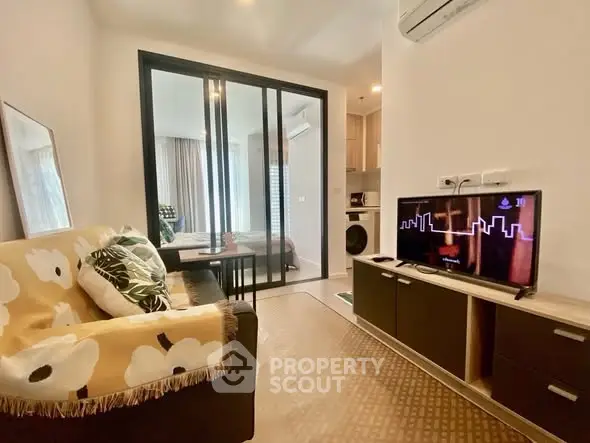 Modern living room with cozy sofa and TV, open layout to bedroom, stylish decor.