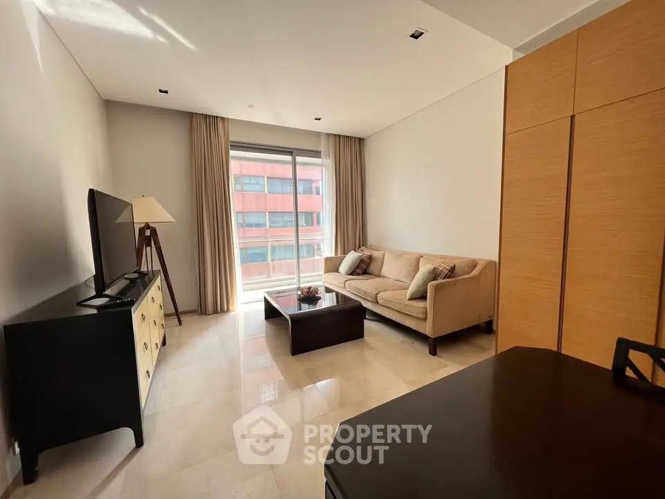 Modern living room with natural light, cozy sofa, and sleek TV setup in a stylish apartment.