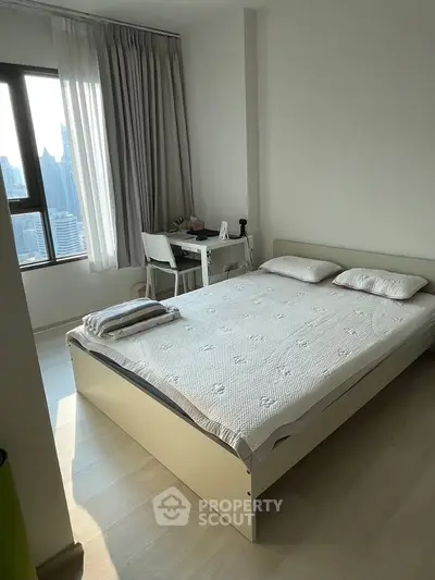 Bright and cozy bedroom with city view, featuring a comfortable bed and study desk, perfect for urban living.