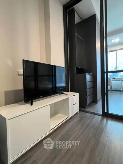 Modern living room with sleek TV stand and sliding glass door leading to bright balcony.