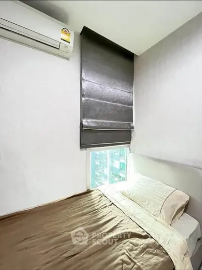 Cozy bedroom with modern air conditioning and city view window, perfect for urban living.