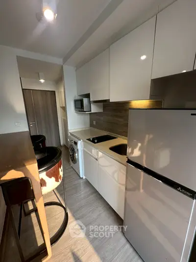 Modern kitchen with sleek appliances and stylish bar seating in a compact layout.