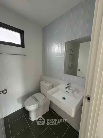 Modern bathroom with sleek fixtures and minimalist design, featuring a wall-mounted sink and compact toilet.
