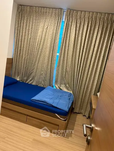 Cozy bedroom with wooden flooring and elegant curtains, featuring a comfortable bed and modern design.