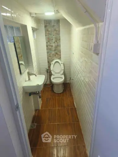 Compact modern bathroom with white tiles and wooden flooring