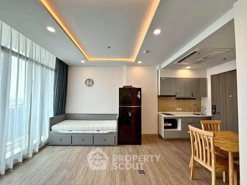 Modern open-layout living room with kitchen, featuring sleek design and ample natural light.
