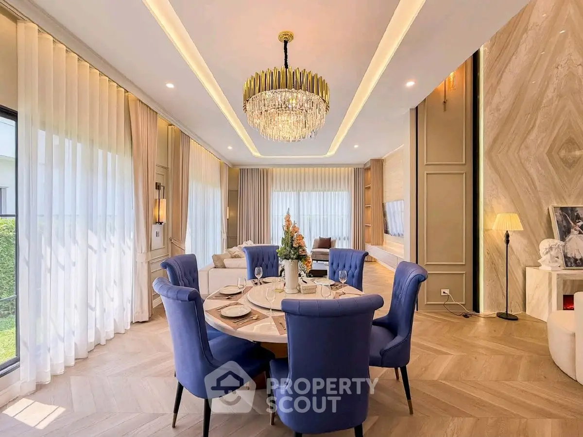 Luxurious dining room with elegant chandelier and plush blue chairs in a modern home