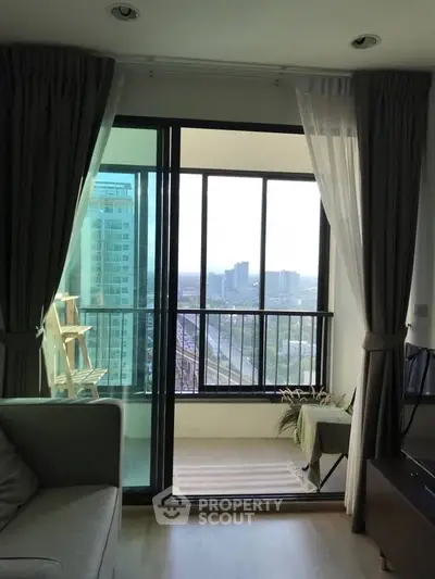 Modern living room with balcony offering stunning city view and ample natural light.