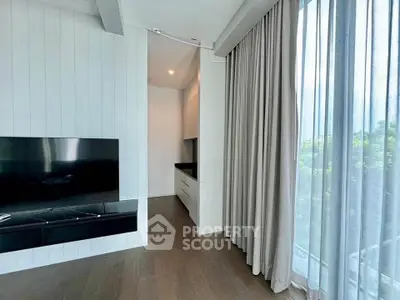 Modern living room with sleek TV setup and floor-to-ceiling curtains
