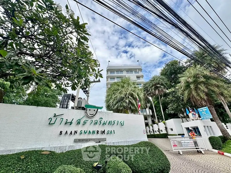 Charming residential building entrance with lush greenery and welcoming signage.