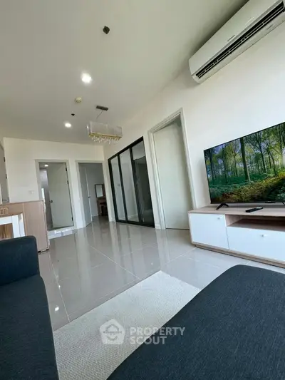 Modern living room with sleek design, large TV, and air conditioning in a bright apartment.