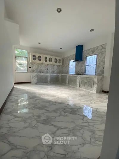 Spacious kitchen with elegant marble flooring and modern cabinetry