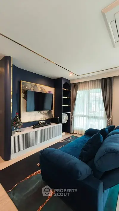 Luxurious living room with modern decor, plush blue sofa, and large TV, perfect for relaxation and entertainment.