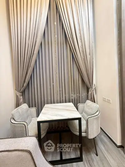 Elegant small dining area with modern chairs and floor-to-ceiling curtains in a cozy apartment.