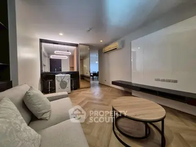 Modern living room with stylish furniture and open layout, featuring a washing machine and sleek lighting.