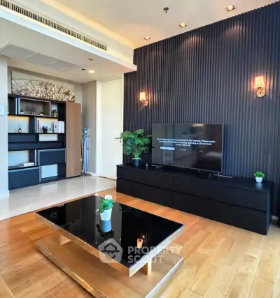 Modern living room with stylish decor and sleek furniture, featuring a large TV and elegant lighting.