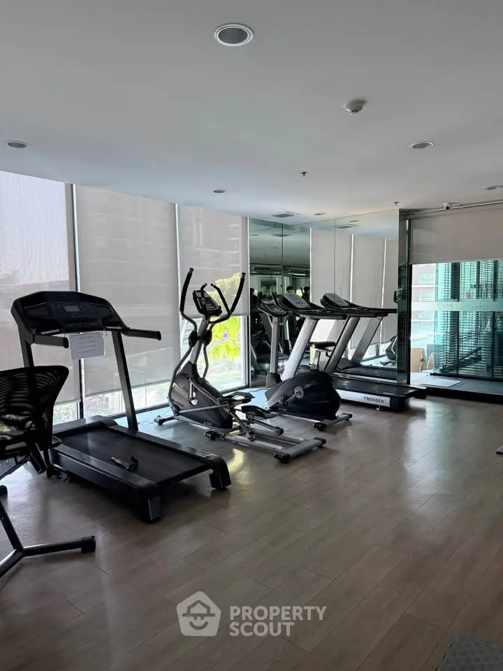 Modern gym with state-of-the-art equipment and large windows in a residential building.