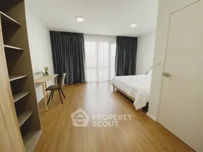 Spacious modern bedroom with wooden flooring and large window