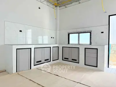 Modern kitchen under construction with sleek cabinetry and marble backsplash