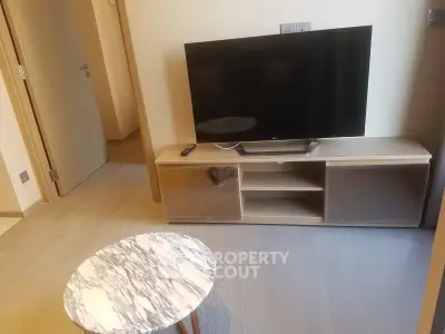 Modern living room with sleek TV stand and marble coffee table in cozy apartment.