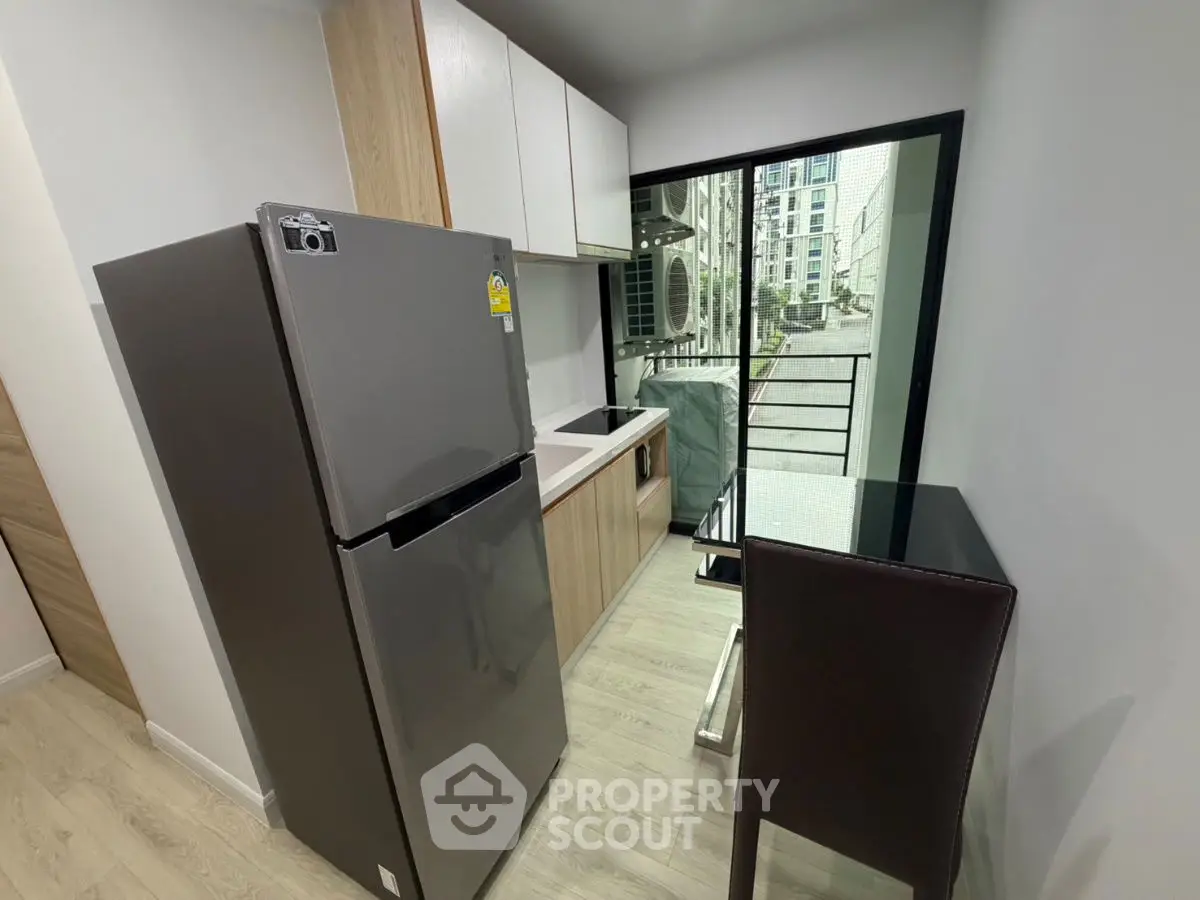 Modern kitchen with sleek appliances and balcony view in urban apartment